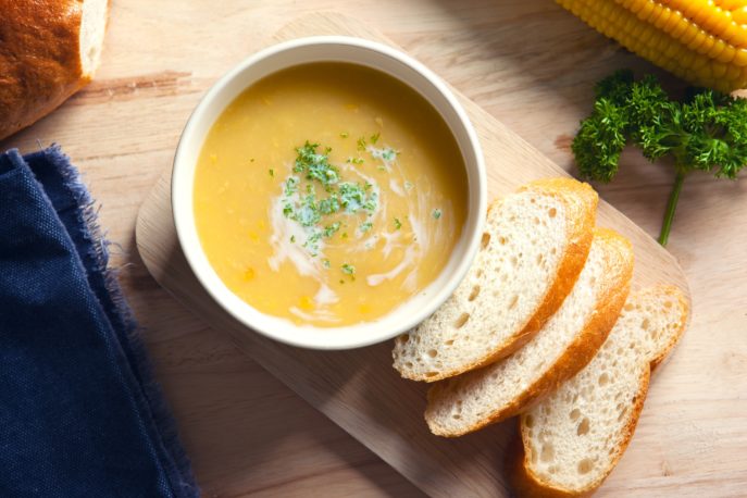corn soup with sliced bread on wooden board